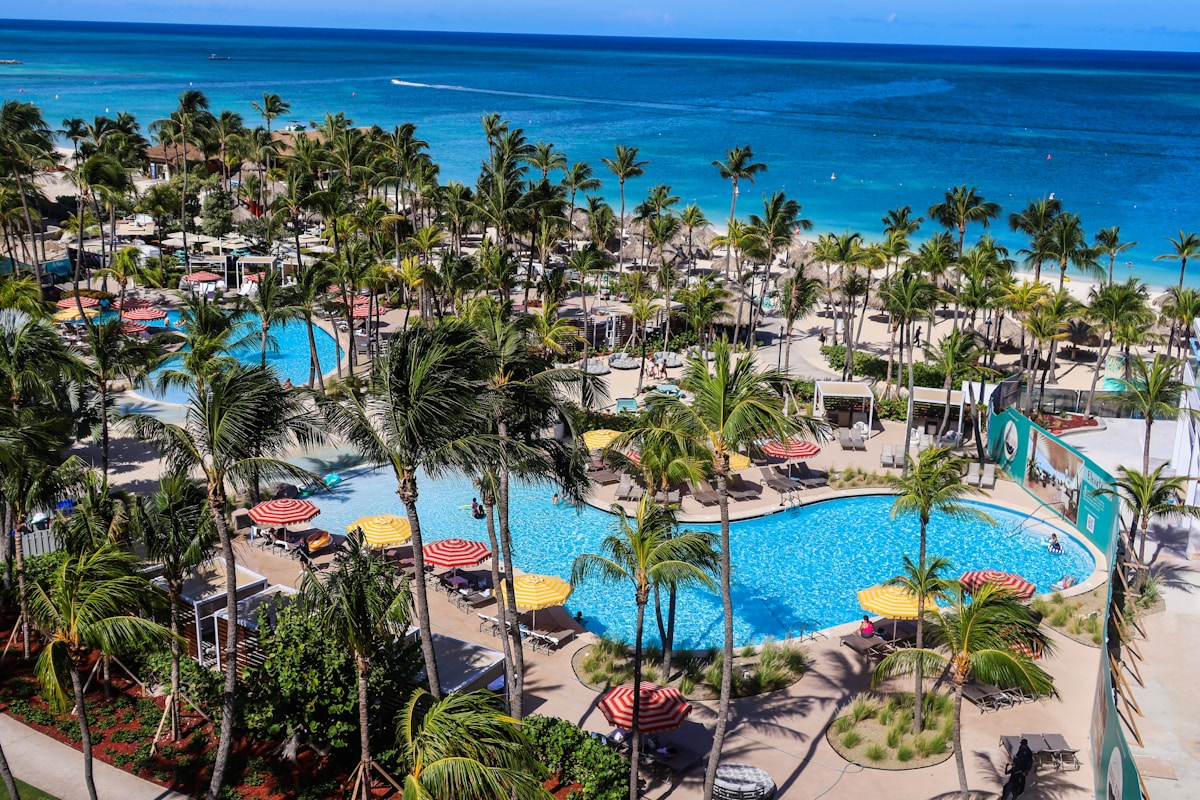 Tropical all-inclusive resort with pools and palm trees by the ocean in Aruba